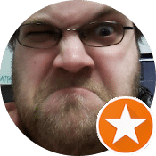 Funny close-up of a man with glasses making a silly face, winking and squinting with a scrunched expression. Orange star badge overlay.